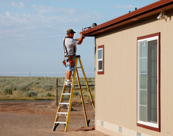 A professional technician installing seamless gutters on a residential home in Cloverdale, CA, with tools and materials neatly organized.