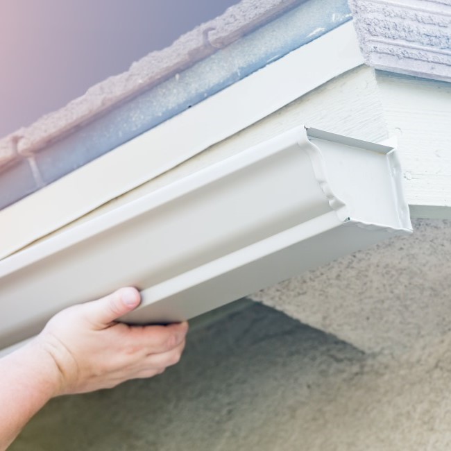 Low angle view of white colored gutter being installed on home