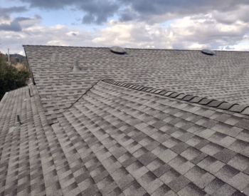 Newly installed asphalt shingle roof by a Cotati roofer under a cloudy sky, showcasing professional roofing services.