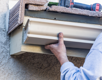 A skilled expert is installing new seamless gutters on a house in Greenbrae, CA.