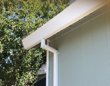 Replacement gutters on a lovely home in Rohnert Park, CA, with blooming trees background.
