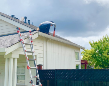 A skilled worker on a cloudy day replacing gutters on a stunning Ross, California, property.
